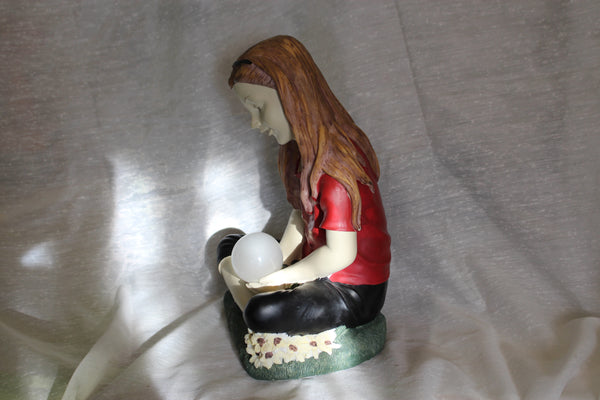 Resin statuette of a sitting girl with a glass globe